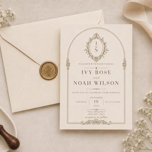 Könnte beinhalten: Hochzeitseinladung mit cremefarbenem Umschlag und Karte. Die Karte zeigt die Namen "Ivy Rose" und "Noah Wilson" mit dekorativen Elementen und dem Datum "19. September 2016". Ein goldener Wachssiegel und ein Holzstempel sind ebenfalls zu sehen.