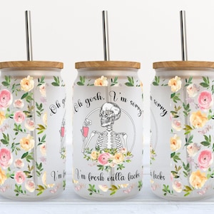 May include: A frosted glass tumbler with a bamboo lid and a stainless steel straw. The tumbler features a floral design with pink and yellow roses and green leaves. The text on the tumbler reads "Oh gosh. I'm sorry. I'm fresh outta fucks."