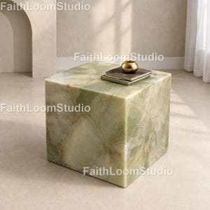 May include: A square, green marble side table with a gold-colored decorative bowl and two books on top. The table has a natural, veined pattern. The words "FaithLoomStudio" are printed on the table.