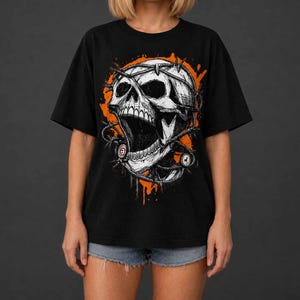 Puede incluir: Una camiseta negra de manga corta con un gran estampado gráfico de una calavera blanca envuelta en alambre de espino sobre un fondo naranja de salpicaduras circulares. La calavera tiene la mandíbula abierta y pequeños detalles.