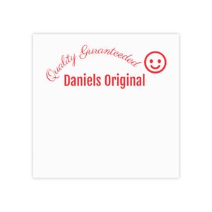 Könnte beinhalten: Ein weißes Quadrat mit rotem Text und einem Smiley-Symbol. Der Text lautet "Quality Guaranteed" in einer kursiven Schriftart, mit "Daniels Original" in einer fetten, serifenlosen Schriftart. Das Smiley-Gesicht befindet sich in der oberen rechten Ecke.