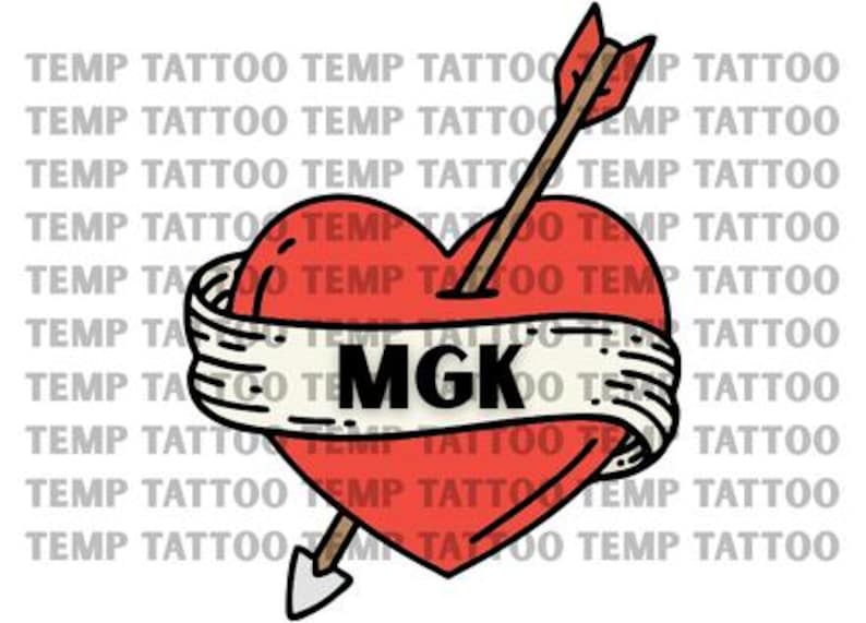 May include: A temporary tattoo design featuring a bright red heart pierced by an arrow with a brown shaft and a grey tip. A white banner with black outlines wraps around the heart, displaying the bold black text MGK in the center.