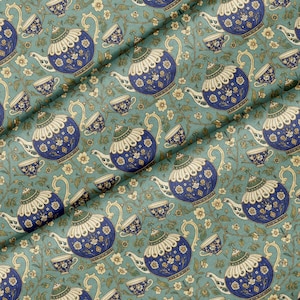 Könnte beinhalten: Ein Stoffmuster mit einem sich wiederholenden Design aus blauen und weißen Teekannen und Teetassen auf einem salbeigrünen Hintergrund. Die Teekannen haben komplizierte Blumendetails, goldene Akzente und grüne Deckel, durchsetzt mit zarten Ranken.