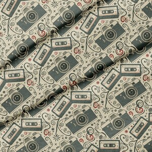 May include: A beige fabric featuring a repeating pattern of dark gray vintage cameras and cassette tapes, accented with small red circular motifs and black swirling line designs that connect the various camera and tape illustrations.