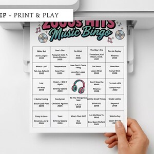 May include: A printed 2000s Hits Music Bingo game sheet with song titles and artists. The sheet is white with a colorful header and is being printed from a printer. The words "NO PREP - PRINT & PLAY" are at the top.