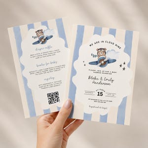 May include: Two rectangular baby shower invitation cards featuring a light blue and cream vertical striped background. The cards display a watercolor illustration of a bear in an airplane, text reading We Are In Cloud Nine, and a QR code.
