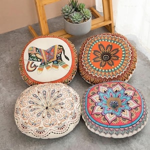 May include: Four round floor cushions with decorative designs. One cushion has a colourful elephant, the others feature mandala patterns in orange, brown, pink, and blue. These cushions are ideal for adding a bohemian touch to any living space.