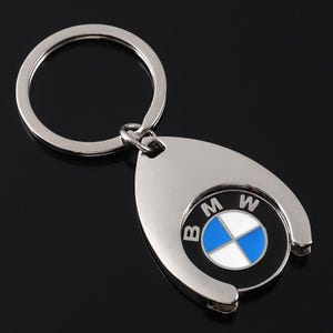 May include: A silver-colored metal keychain with a BMW logo. The logo features a blue and white emblem on a black background, surrounded by the letters "B", "M", and "W". The keychain has a circular ring for keys.