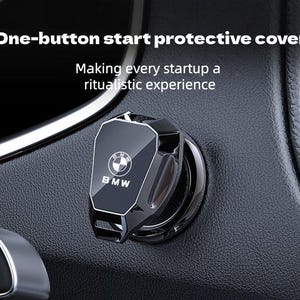May include: A black, angular protective cover for a car engine start button, featuring the BMW logo in white. The text "One-button start protective cover" and "Making every startup a ritualistic experience" is displayed above the button cover.