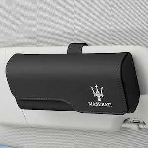 Pode incluir: Um estojo retangular preto para óculos de sol, projetado para o para-sol do carro, feito de material liso com fecho magnético. A parte frontal apresenta o logótipo do tridente Maserati e o texto MASERATI em branco num para-sol cinzento.