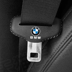 Könnte beinhalten: Nahaufnahme eines schwarzen Ledersitzes mit einem Sicherheitsgurtschloss. Die Schnalle hat eine schwarze Lederabdeckung mit dem BMW-Logo und dem Wort "BMW". Der Sitz hat sichtbare Nähte.