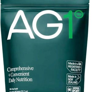 May include: A teal pouch with the text "AG1" in large white letters. The pouch also features the text "Comprehensive + Convenient Daily Nutrition" and "30-Day Supply Net Wt 360 Grams (12.7 oz)." Additional text includes "Made in a TGA Registered Facility," "Made in New Zealand," and "Certified Sport."
