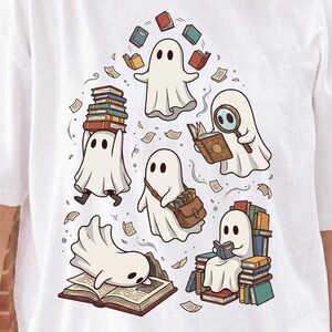 May include: A white t-shirt featuring a graphic illustration of five white ghosts interacting with books. One ghost juggles books, one uses a magnifying glass, one carries a satchel, one rests on an open book, and one sits on a stack of books.