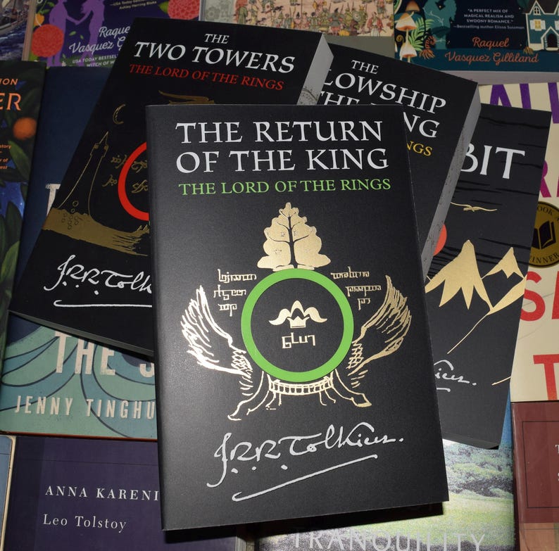 May include: A collection of hardcover books from "The Lord of the Rings" series. The books have black covers with gold and green accents. The title "The Return of the King" is prominently displayed on the front cover, along with the author's signature.