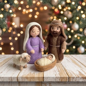 May include: A needle-felted nativity set featuring a figure in a lavender dress with a white head covering, a figure in a brown robe with a headpiece, a small infant wrapped in white fabric in a brown manger, and a small white and tan sheep.