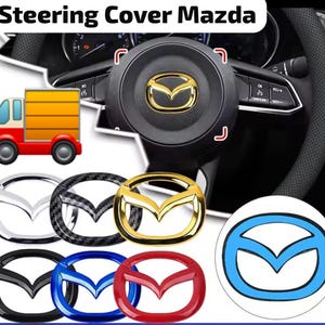 Può includere: Una collezione di emblemi per volante Mazda in varie finiture, tra cui oro, cromo, fibra di carbonio, nero, blu e rosso. Gli emblemi sono circolari con il logo Mazda, mostrati su uno sfondo di un volante di colore nero.