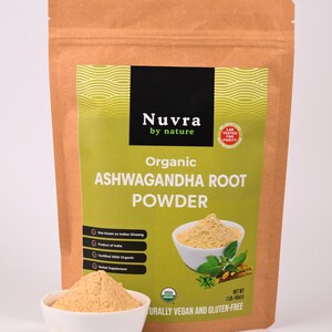 May include: A brown paper bag of organic ashwagandha root powder with a white bowl of powder in front. The bag has a green label with the text "Nuvra by nature" and "Organic Ashwagandha Root Powder". The product is USDA organic, vegan, and gluten-free.