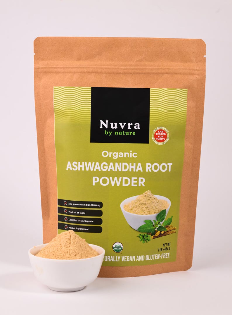 May include: A brown paper bag of organic ashwagandha root powder with a white bowl of powder in front. The bag has a green label with the text "Nuvra by nature" and "Organic Ashwagandha Root Powder". The product is USDA organic, vegan, and gluten-free.