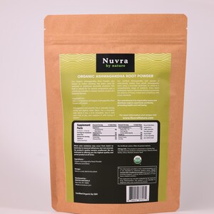 May include: A brown paper bag of Nuvra Organic Ashwagandha Root Powder. The bag has a green and white label with the brand name and product information. The label includes the text "Supplement Facts" and "Certified Organic by QAI".