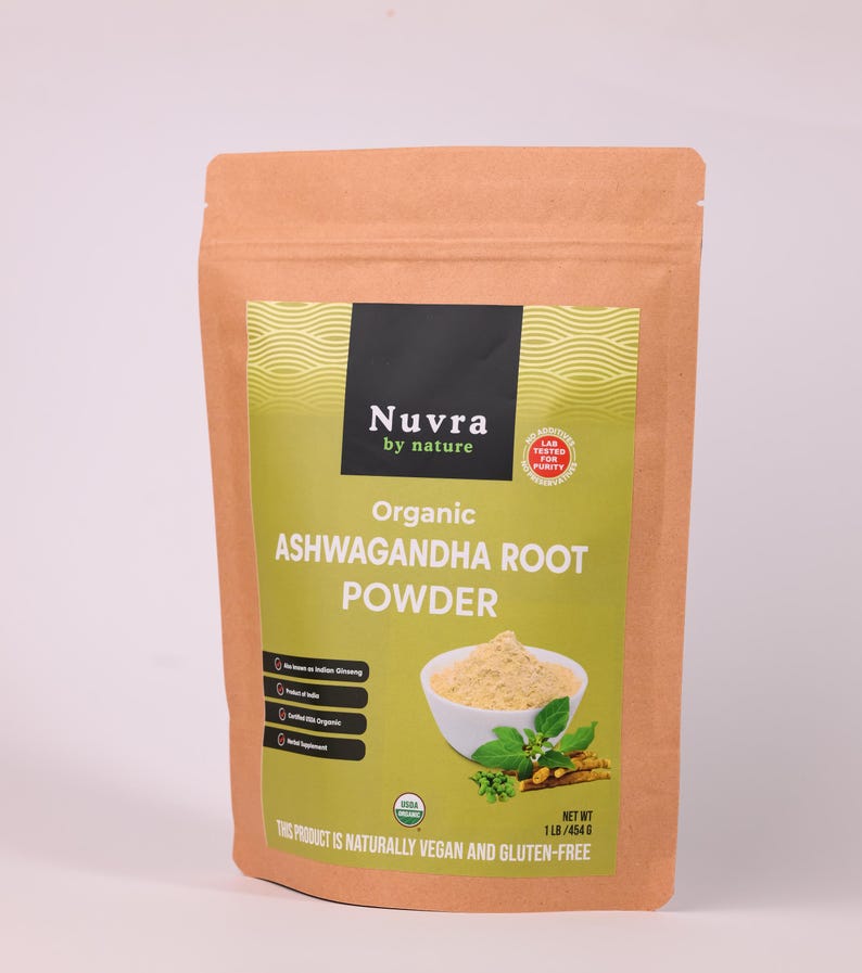 May include: A brown paper bag of Nuvra Organic Ashwagandha Root Powder. The bag has a green and yellow label with the product name and a picture of the powder in a white bowl with green leaves. The text on the bag says the product is naturally vegan and gluten-free.