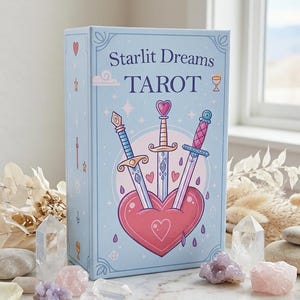 May include: A light blue rectangular tarot deck box titled Starlit Dreams TAROT. The front features an illustration of three swords piercing a large pink heart, surrounded by small stars, hearts, and a cloud icon, all in a pastel color palette.