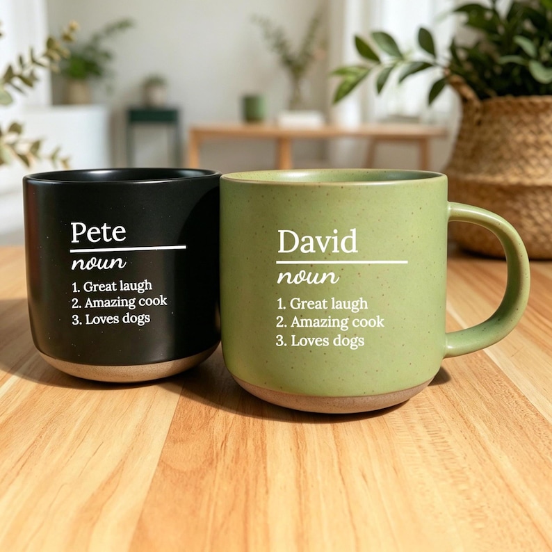 May include: Two ceramic mugs, one black and one green, with the names "Pete" and "David" printed in white. Each mug has a list of three qualities: "Great laugh," "Amazing cook," and "Loves dogs."