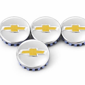 May include: Four silver hubcaps with a yellow Chevrolet logo. The hubcaps have a blue base and are arranged in a group on a white background. The Chevrolet logo is a yellow bow tie.