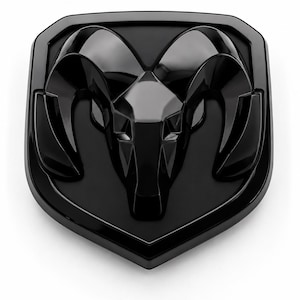 Puede incluir: Un emblema negro brillante que presenta una cabeza de carnero estilizada con grandes cuernos curvados, centrada dentro de un borde en forma de escudo. El diseño es monocromático con una superficie lisa y reflectante y contornos geométricos.