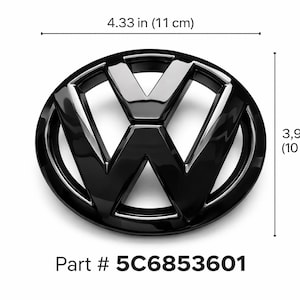 May include: A glossy black Volkswagen emblem, oval-shaped, with the VW logo in the center. The emblem measures 4.33 inches (11 cm) wide and 3.9 inches (10 cm) high. The part number is 5C6853601.