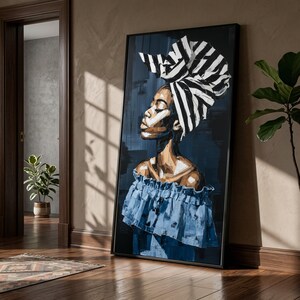 May include: An abstract painting of a woman with a blue ruffled top and a black and white striped head wrap. The artwork is framed in black and leans against a wall. The colour palette includes shades of blue, brown, and white.