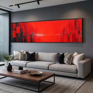 Könnte beinhalten: Ein großes, horizontales, rechteckiges Wandbild mit einer leuchtend roten abstrakten Komposition und dunklen, vertikalen geometrischen Formen. Das Kunstwerk ist in einem dünnen schwarzen Rahmen gefasst und hängt über einem langen, hellgrauen Sofa.