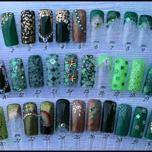 May include: Thirty nail art designs featuring green, gold, and silver glitter, shamrocks, and other St. Patrick's Day themed designs.