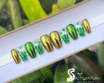 May include: Set of ten press-on nails with a gold and green metallic finish. Each nail is decorated with green shamrock glitter.