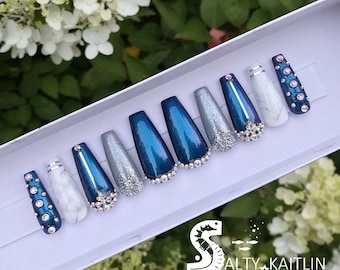 May include: Set of ten blue and silver press-on nails with rhinestones. The nails are in a white box with the text "Salty Kaitlin Beachy Nails & More".