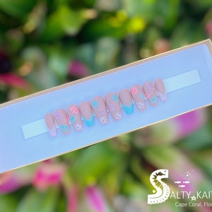 May include: A set of ten false nails with a light pink base and a white tip. Each nail has a different design featuring a small butterfly with glitter accents in shades of pink, blue, and green.