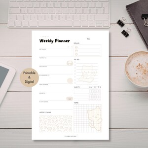 May include: A white weekly planner with a minimalist design, featuring sections for each day, goals, and habits. The planner includes a cute cat illustration and the text "Printable & Digital". A cup of coffee, a keyboard, and a notebook are also visible.