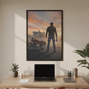 May include: Framed print of a man standing in front of a red motorcycle and a house at sunset. The man is wearing a leather jacket and jeans, holding a helmet. The motorcycle is parked on a road.
