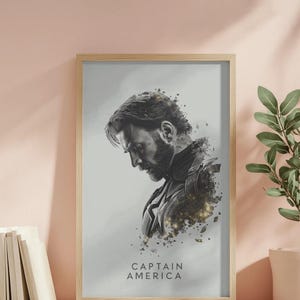 May include: Framed art print featuring a grayscale portrait of Captain America. The artwork shows a side profile of the character with a beard, set against a light gray background. The words "CAPTAIN AMERICA" are printed at the bottom.