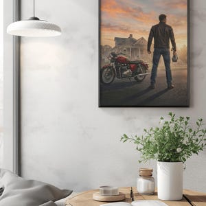 May include: Framed print featuring a man standing next to a red motorcycle, facing away from the viewer. The background shows a house and a sunset sky. The man is wearing a leather jacket and jeans, holding a helmet.
