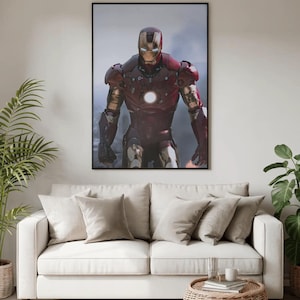 K&ouml;nnte beinhalten: Ein gerahmter Druck von Iron Man in seiner rot-goldenen R&uuml;stung, vor einem rauchigen Hintergrund. Das Kunstwerk h&auml;ngt &uuml;ber einem wei&szlig;en Sofa mit beigen Kissen, einem Beistelltisch aus Korbgeflecht und Topfpflanzen.
