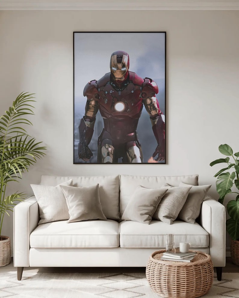 K&ouml;nnte beinhalten: Ein gerahmter Druck von Iron Man in seiner rot-goldenen R&uuml;stung, vor einem rauchigen Hintergrund. Das Kunstwerk h&auml;ngt &uuml;ber einem wei&szlig;en Sofa mit beigen Kissen, einem Beistelltisch aus Korbgeflecht und Topfpflanzen.
