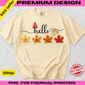 Peut inclure: Un t-shirt à manches courtes de couleur crème avec le texte hello FALL en écriture noire. Le motif comprend un bonnet en tricot rouge, une paire de chaussettes à motifs et quatre feuilles d'érable jaunes, orange, rouille et rouges.