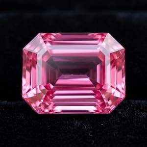 Puede incluir: Una gema de color rosa vibrante tallada en forma de esmeralda rectangular con facetas nítidas y limpias que reflejan la luz. La piedra muestra un color rosa profundo y saturado en toda su estructura, exhibiendo una calidad clara y transparente.
