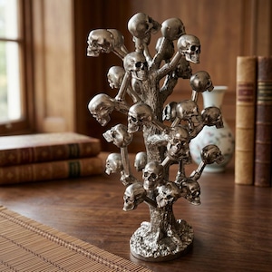 May include: A metallic silver-toned sculpture shaped like a tree with numerous human skulls attached to the branches. The textured trunk stands on a circular base, and the entire piece features a weathered, antique finish with detailed bone structures.