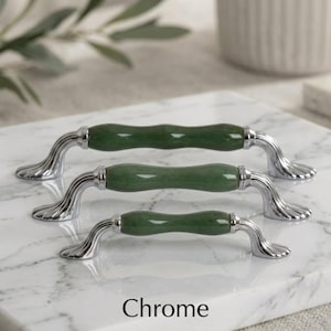 May include: Three cabinet pulls arranged in a vertical row, each featuring a smooth, cylindrical green stone center section flanked by polished chrome metal ends with a fluted, fan-like base design. The word Chrome is printed at the bottom.