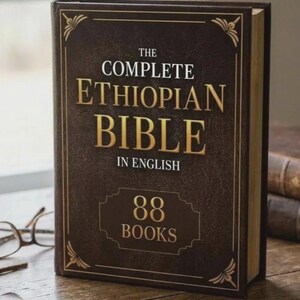 Op de afbeelding: Een donkerbruin hardcover boek met de titel "The Complete Ethiopian Bible in English" met gouden letters en accenten. Het boek toont "88 Books" op de voorkant. Het boek ligt op een houten oppervlak.