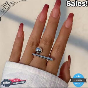 May include: A silver ring with a spherical top and a straight bar design. The ring is worn on a finger with long, ombre-colored nails. The image also includes the text "Sales!" and "Top Seller!"