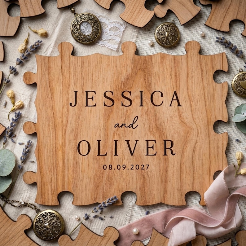 May include: A wooden puzzle piece engraved with "JESSICA and OLIVER" and the date "08.09.2027". The puzzle is surrounded by other wooden pieces, dried lavender, and vintage lockets.