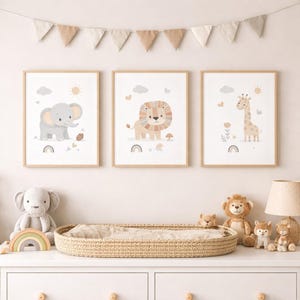 Könnte beinhalten: Drei gerahmte Kunstdrucke mit Tieren, die einen grauen Elefanten, einen Löwen und eine Giraffe zeigen, jeweils mit Sonne, Wolken und einem Regenbogen. Die Drucke sind in hellen Holzrahmen und gehören zu einem Kinderzimmer-Dekorationsset.