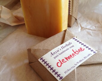 Könnte beinhalten: Eine in braunes Papier verpackte handgemachte Seife mit einem Etikett mit der Aufschrift "Anya's Herbals pure handmade soap Clementine PO Box 1154, So Wellfleet, MA 02663"